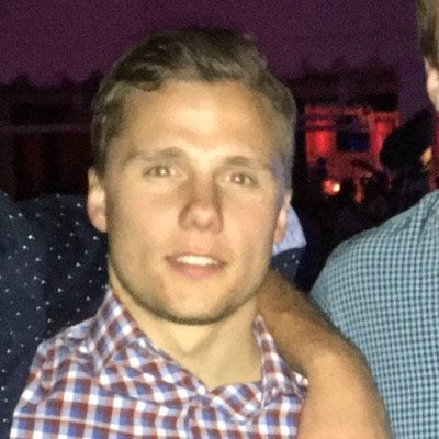 Man standing in a greenhouse with crossed arms, surrounded by plants.