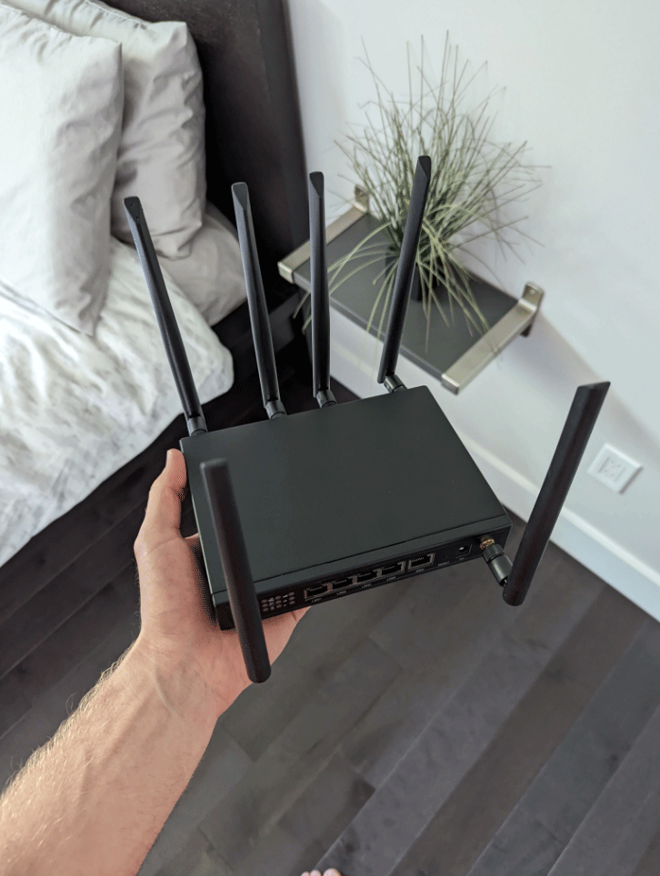 Person holding a black Wi-Fi router with multiple antennas.