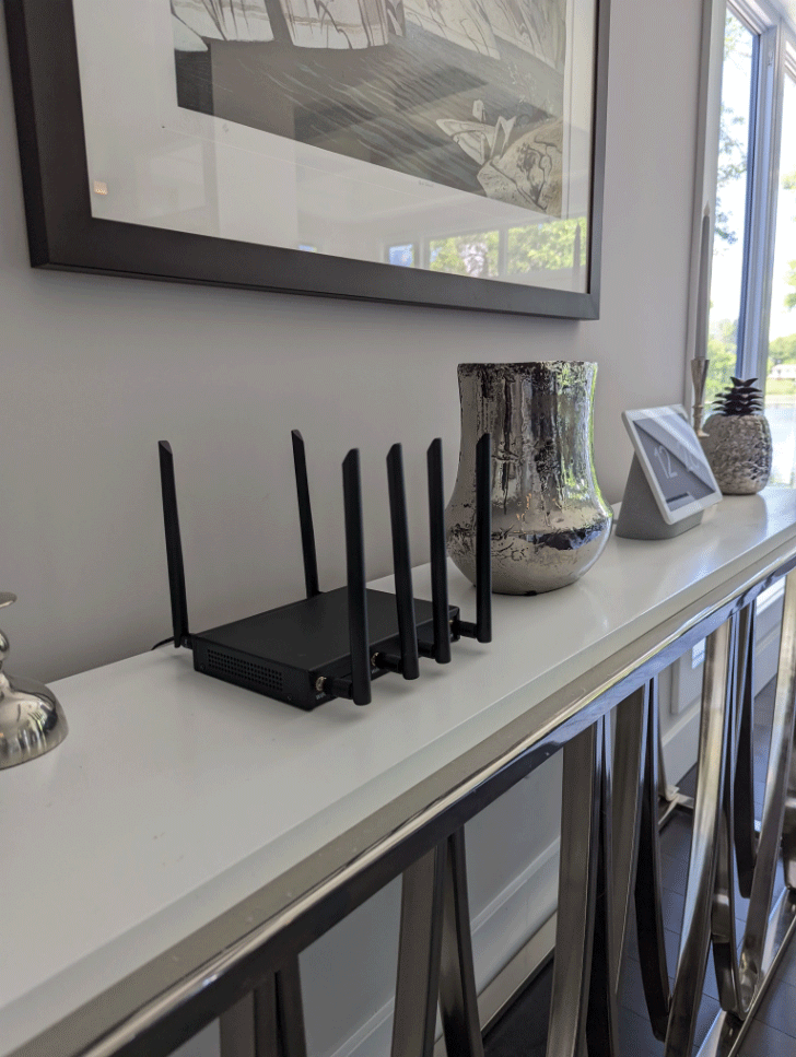 Modern Wi-Fi router on a decorative console table, near a vase and artwork.